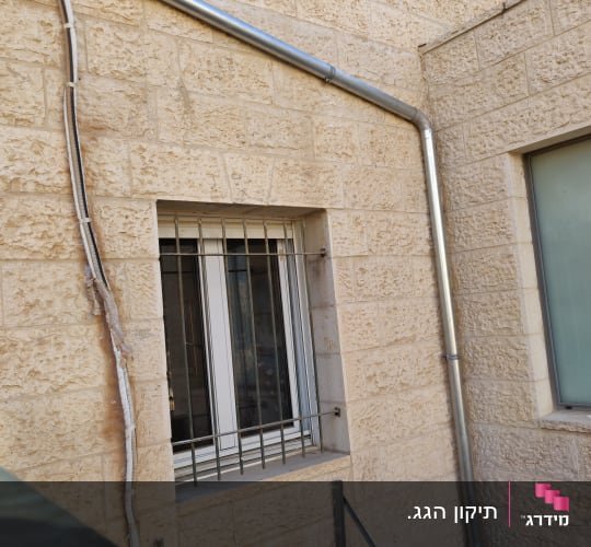 צינור מתכת על קיר אבן ליד חלון